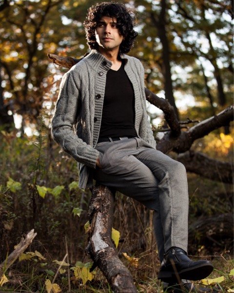 Young man sitting on a fallen tree in autumn