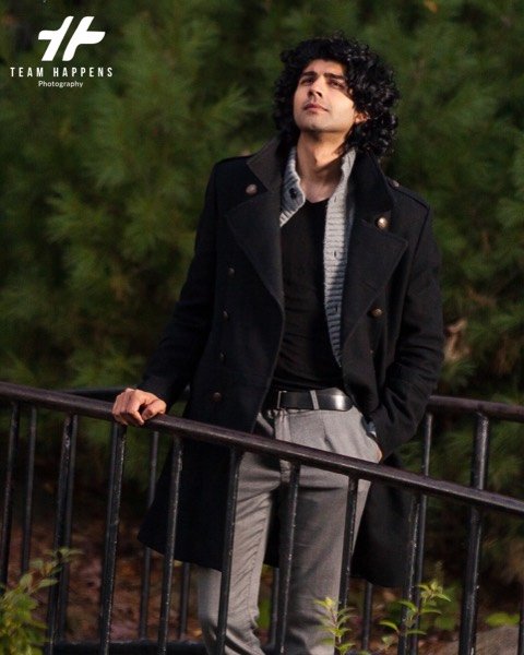 Young man in a black coat by a railing