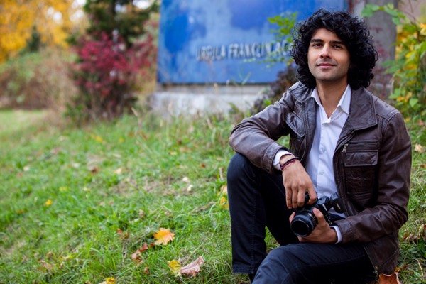 Man in a leather jacket kneeling on the grass